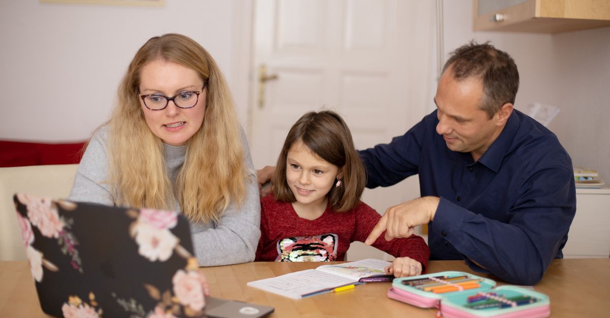 A family is engaged in homeschooling, using technology to learn together in a cozy home setting.